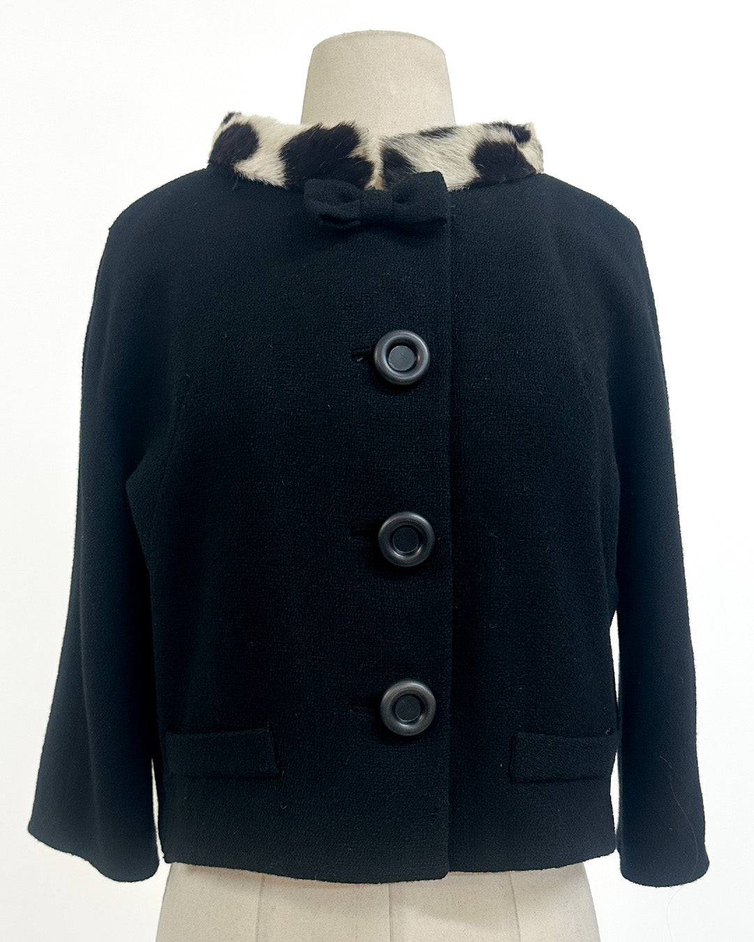 Navy blue coat with fur collar on a mannequin against a white background