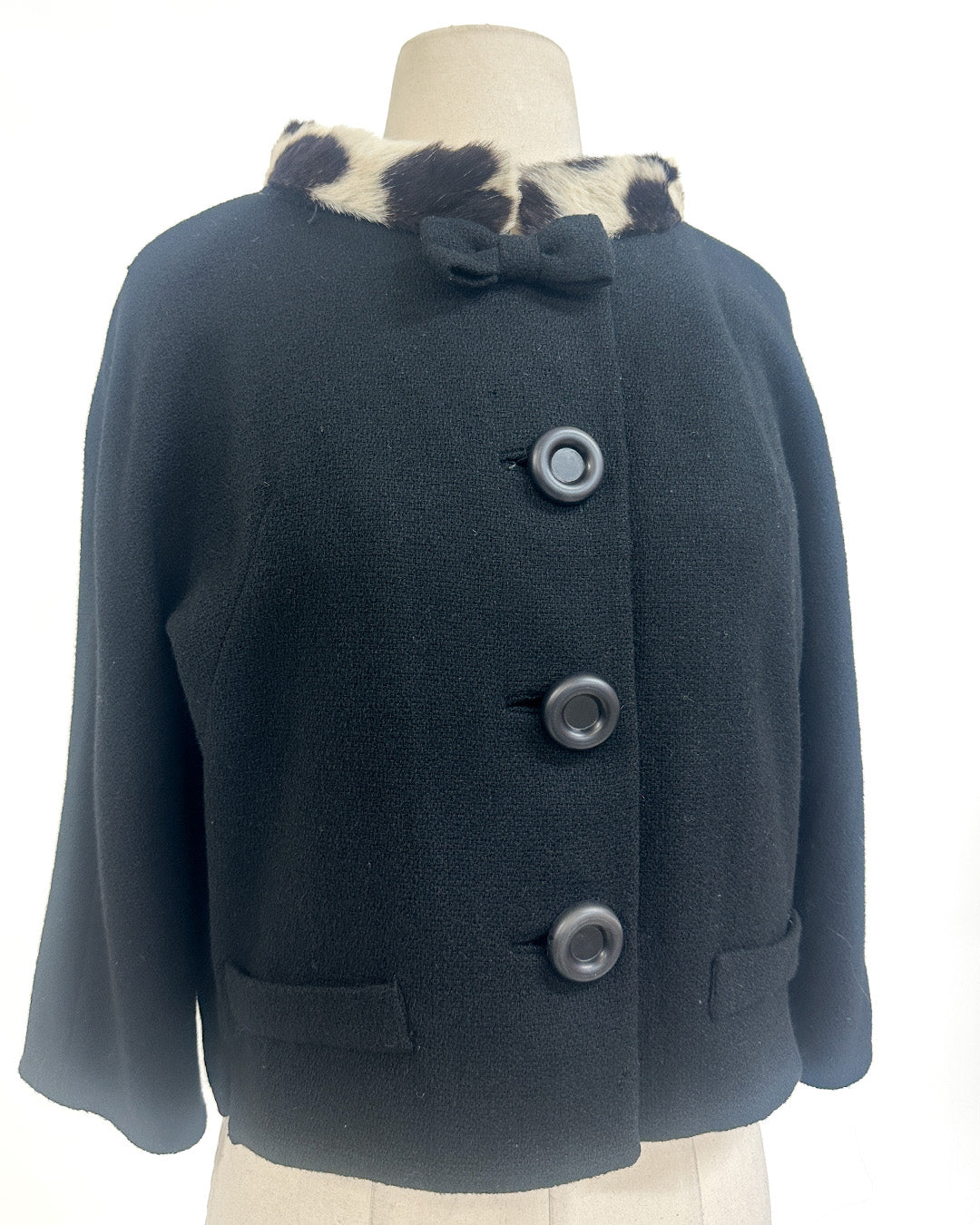 Navy blue coat with fur trim on a mannequin against a white background