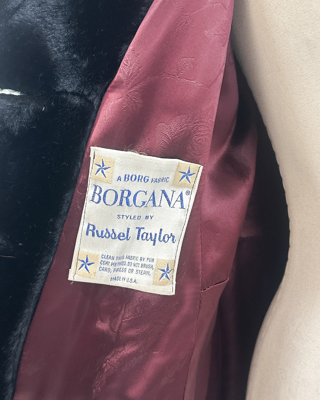 Borgana fabric label on a maroon fabric with black fur trim.